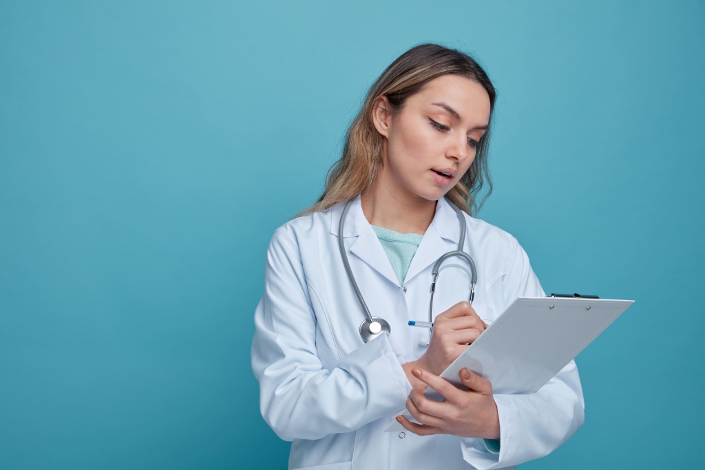 impressed-young-female-doctor-wearing-medical-robe-stethoscope-around-neck-writing-with-pen-clipboard.jpg